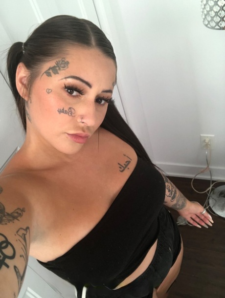Her boyfriend Rick Hard strips and exhibits her tattooed body with large breasts and a prominent chest.