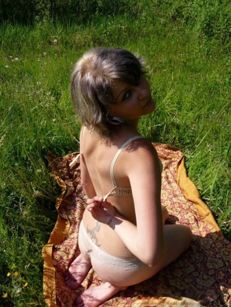 Horny MILF member stripping and posing naked on a blanket in the open air.