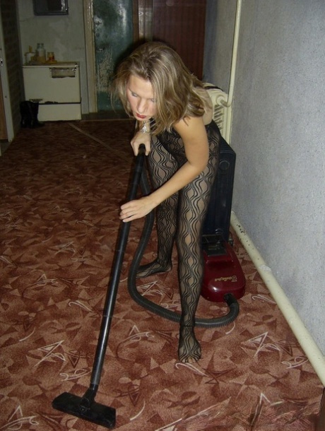 A fat lady who wears red lipstick is seen in her bodystock vacuuming.