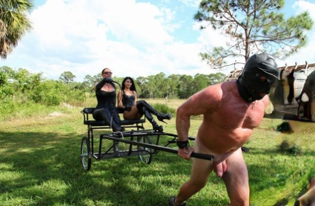 Femdoms Esmie Lee & Venus impart a lesson to their naked muscular slave outside of the house.