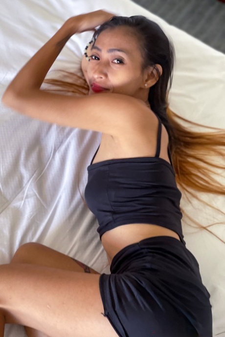 Adorable petite Asiatic female model Mjane dresses in a seductive black top.