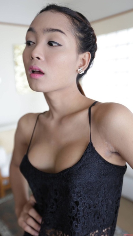 The adorable Asian female displays her small tits while donning an alluring black dress for play.