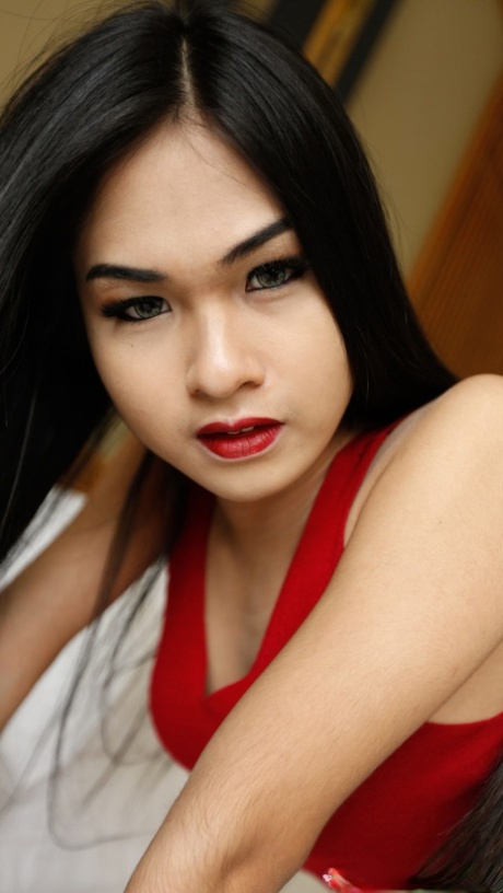 While being tamed in a seductive red dress, a hot Asian shemale performs oral sex on the opposite side of the tongue.