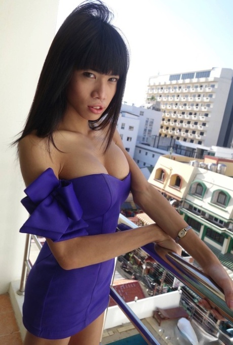 Looking cute, Jenny wears a purple dress and flaunts her breasts on the balcony.