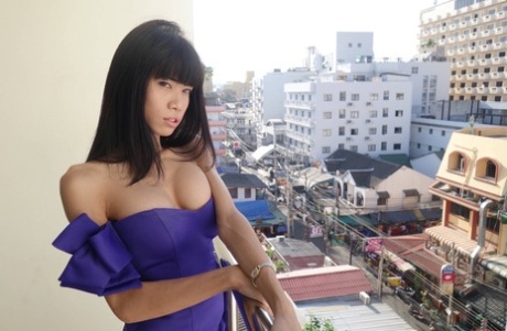 At the balcony, a lovely ladyboy named Jenny is seen wearing a pretty dress and flaunting her breasts.