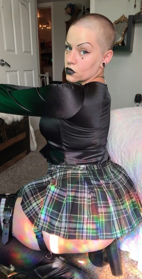 In a Bald MILF top, Miss Goth Booty exposes her large buttocks while wearing a plaid skirt.