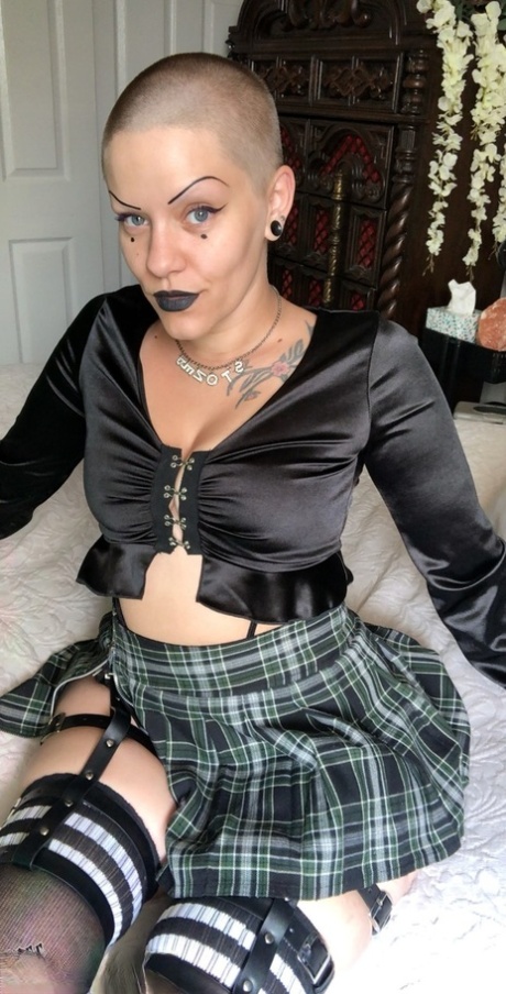 With a Bald MILF label, Miss Goth Booty flaunts her large buttocks and wears a plaid skirt.