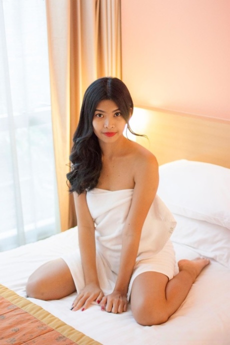 Chuun, a brunette and Asian student, displays her tender abdomen and vagina on a bed.