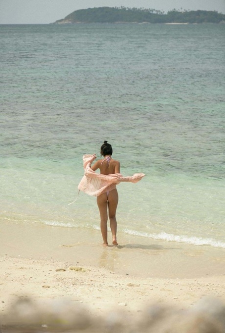 A charming young woman from Asia exhibits her short legs and erect asses while lounging at the beach.