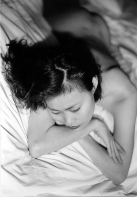 In this black and white scene, an Asian girl exhibits her small stomach with a petite body.