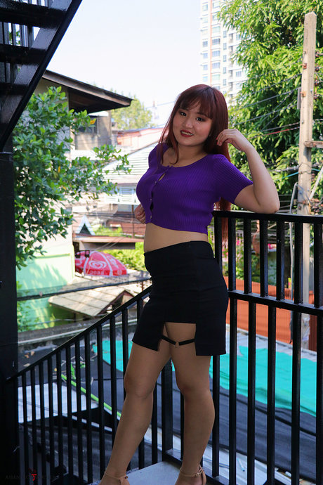 A red-headed Asian beauty is spotted on the stairs, dressed in a flashy skirt and purple top.