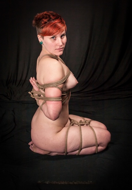 A naked redheaded babe with big tits and blindfolded eyes is observed in her surroundings.