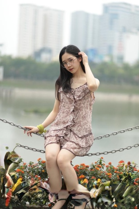 The charming sexy Asian woman exudes confidence while wearing a pleated short dress in the open air.