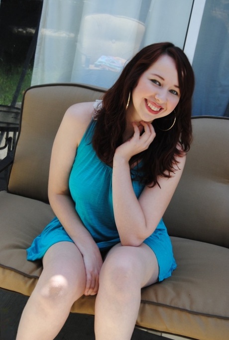 A slick-haired brunette with blonde hair who is an amateur, sitting on the sofa next to her stunning blue dress.