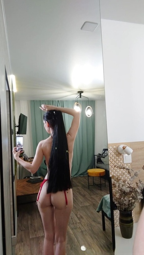 MILF, with a flowing ponytail, appears attractive while staring at the half-naked mirror.