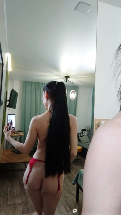 A brunched brunette wearing a ponytail and posing in a half-naked reflection with seductive appeal.