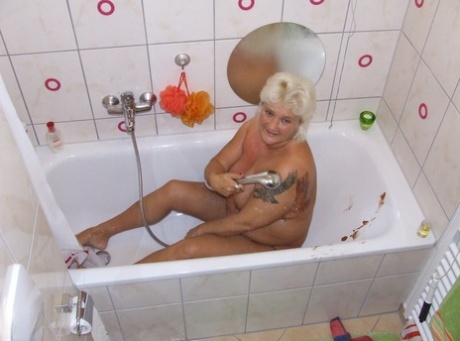 Katja, a large blonde who is also overweight and has a well-endowed body, pours chocolate milk onto her breasts while bathing in the tub.