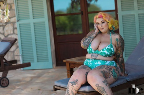 While tattooing BBW with rainbow hair, Galda Lou displays her huge melons and big ass.