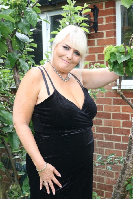 As she poses in a long dress, Christina, the overweight blonde, displays her plump busty but attractive figure.