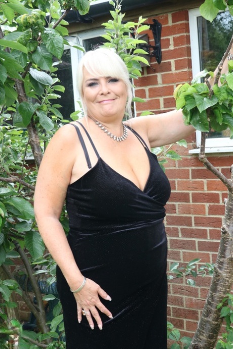 In her long dress, Christina, a fat and mature blonde, displays the hot cleavage.