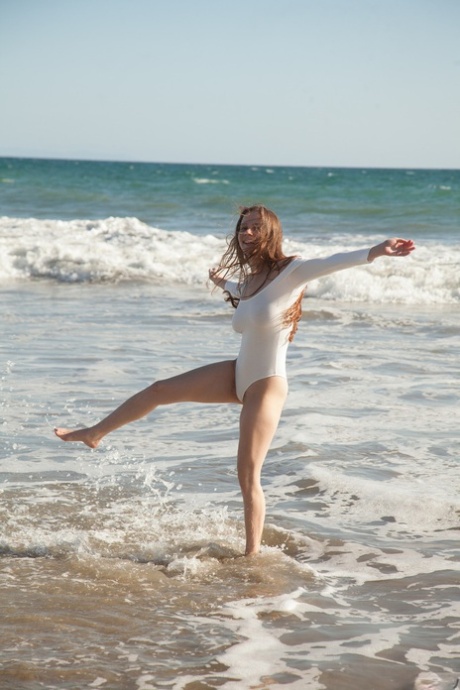 On the beach, Avri Gaines wears a white bodysuit and enjoys playing with her sizable breasts.