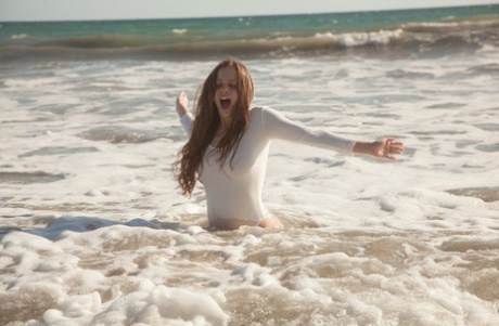 On the beach, Avri Gaines, a young woman in a white bodysuit, plays with her ample bosom.