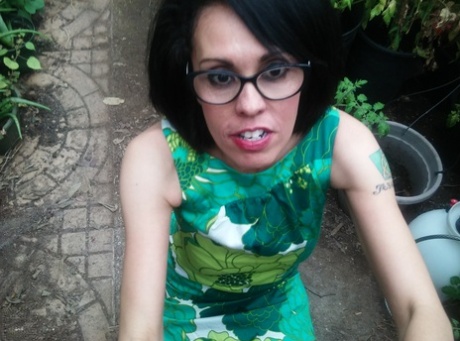 In a cramped garden, Gypsy Vixen puts on her face while wearing glasses.