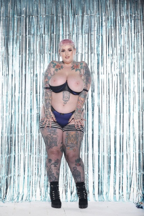 BBW Cherrie Pie's pink-haired appearance includes stripping and flaunting her monster tits and inked booty.