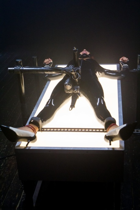 Daisy Ducati, a red-headed ebony female with latex hair, is bound and toyed with.