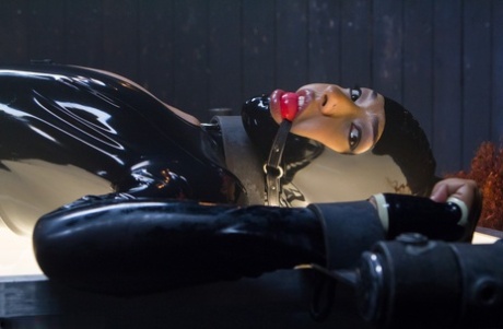 Daisy Ducati, the red-headed ebony female who is covered in latex, is bound and toyed with.