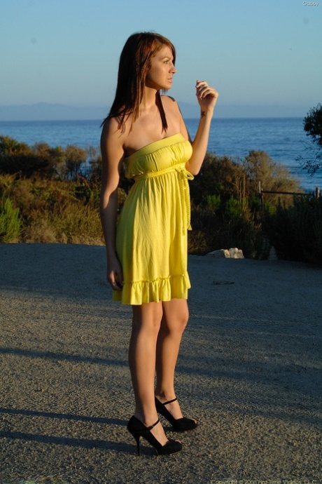 Showing off her cuddly tits, Gabby, the glamorous babe, wears a yellow dress and heels while outdoors.