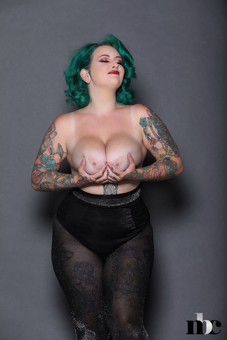 Galda Lou, the chubby but very young girl with green hair, displays her tattooed physique and ample breasts.