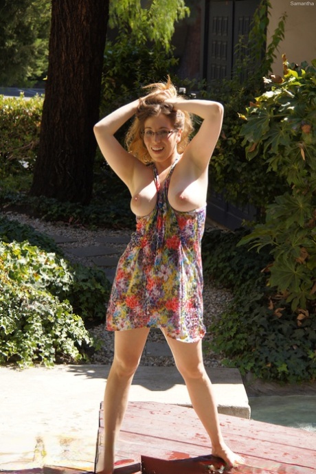 Samantha, sporting a curvy MILF face and eyeglasses, is pushing out her big breasts.