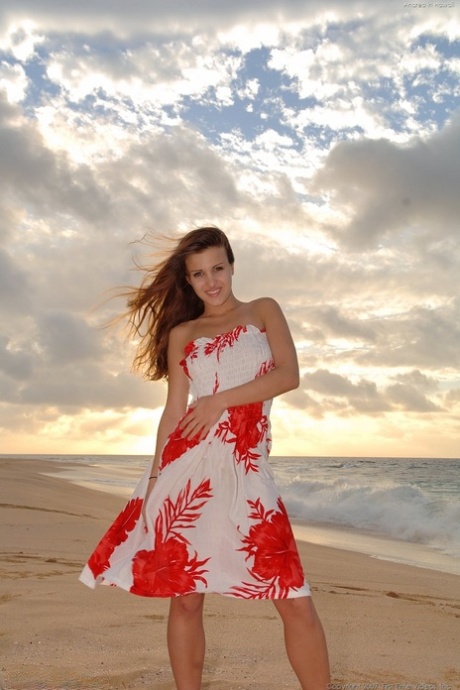 On the beach, a playful Andrea poses in her summer attire, donning a loose dress and posing in the nude.